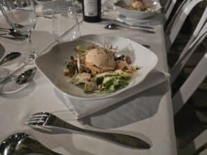 Entrée gastronomique avec salade, mousse onctueuse et jeunes pousses servie sur une nappe blanche élégante.